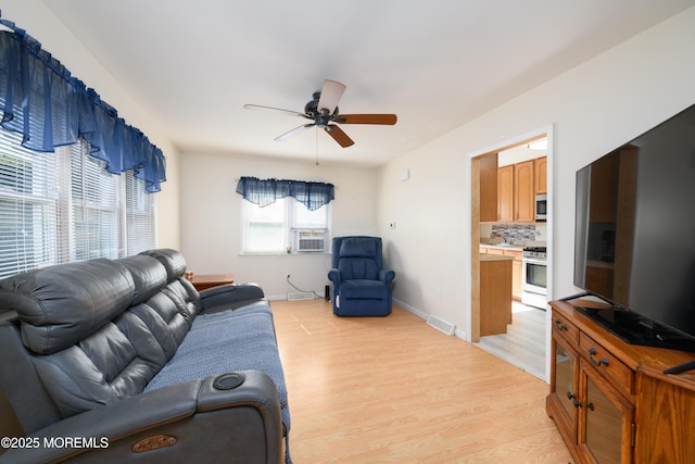 living area with a ceiling fan, visible vents, baseboards, cooling unit, and light wood finished floors