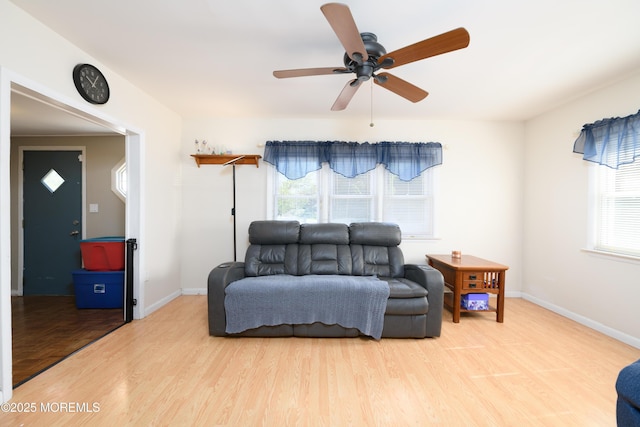 living area featuring a ceiling fan, baseboards, and wood finished floors