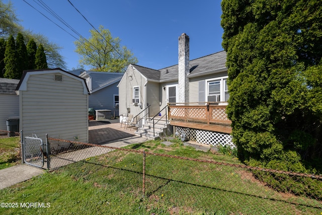 view of front of house featuring a front lawn, a deck, a gate, a chimney, and a patio area