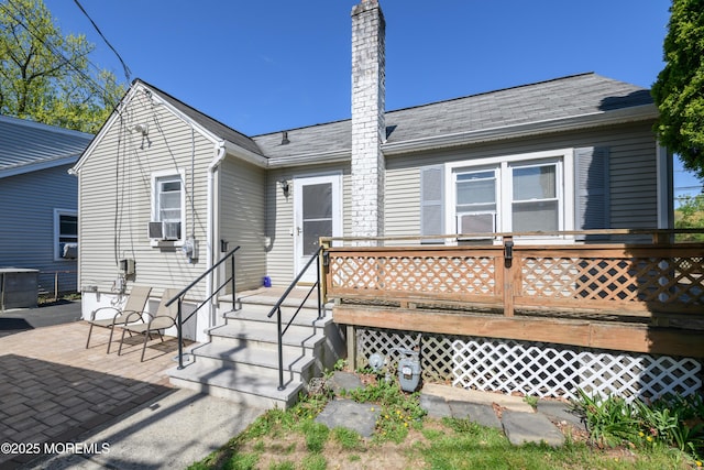 rear view of property with a deck, a chimney, cooling unit, a patio area, and central air condition unit