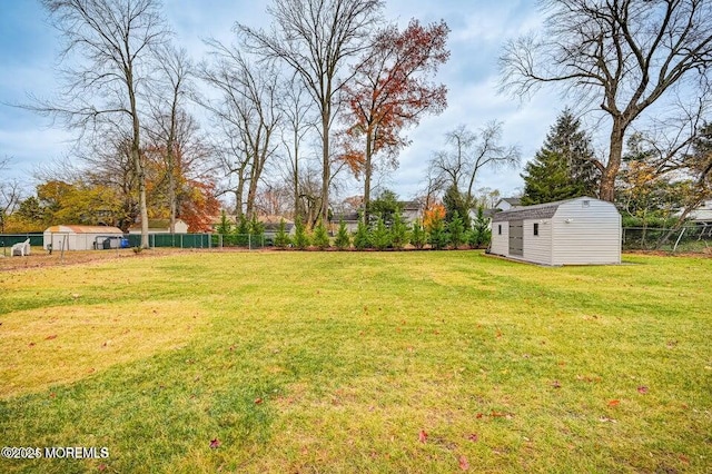 view of yard with fence, an outbuilding, and a shed