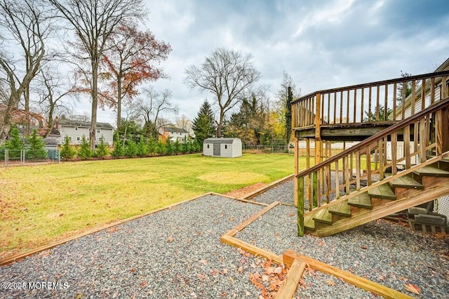 view of yard featuring an outdoor structure, a wooden deck, a fenced backyard, a shed, and stairway