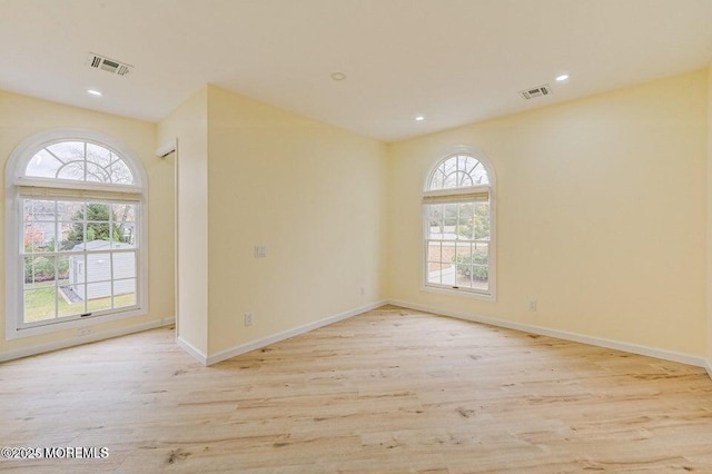 unfurnished room with visible vents, plenty of natural light, and wood finished floors