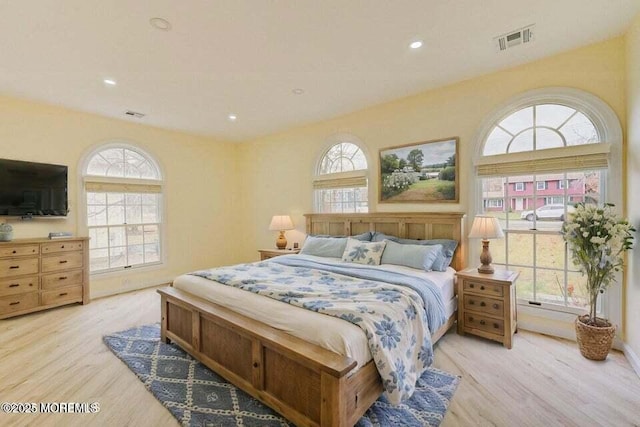 bedroom with visible vents, multiple windows, and wood finished floors