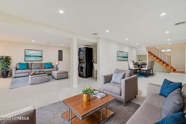 living room with stacked washing maching and dryer, stairway, recessed lighting, and visible vents