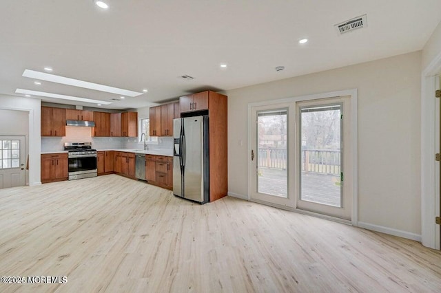 kitchen featuring brown cabinets, appliances with stainless steel finishes, light wood-style floors, light countertops, and visible vents