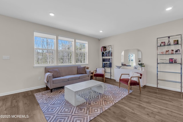 living area with baseboards, arched walkways, wood finished floors, and recessed lighting