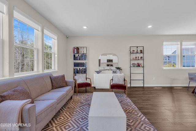 living area featuring recessed lighting, baseboards, wood finished floors, and arched walkways