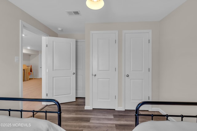 bedroom featuring visible vents, baseboards, and wood finished floors