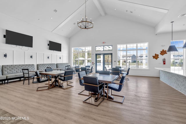 dining room with a healthy amount of sunlight, high vaulted ceiling, beam ceiling, and light wood-style flooring