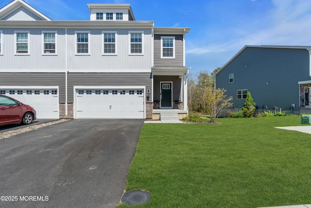 view of front of home featuring an attached garage, driveway, stone siding, and a front yard