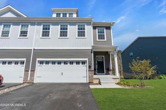 townhome / multi-family property featuring a garage, a front lawn, driveway, and stone siding