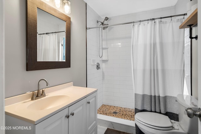 full bath with toilet, a tile shower, and vanity