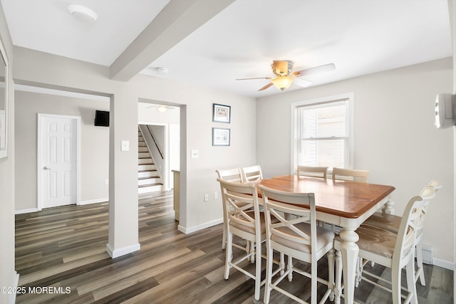 dining space with dark wood-style flooring, ceiling fan, baseboards, and stairway