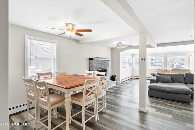 dining space featuring ceiling fan, a baseboard heating unit, a wealth of natural light, and a fireplace