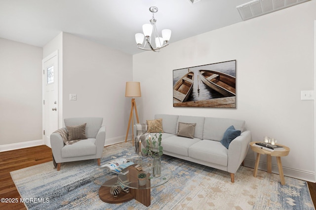 living area featuring baseboards, wood finished floors, a chandelier, and visible vents
