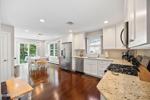 kitchen with visible vents, a sink, a baseboard radiator, stainless steel appliances, and a wealth of natural light