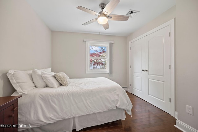 bedroom featuring dark wood finished floors, a ceiling fan, baseboards, visible vents, and a closet