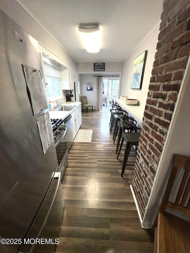 25 O St, Seaside Park, NJ 08752 - kitchen featuring stainless steel appliances, crown molding, white cabinetry, dark wood-style flooring, and light countertops