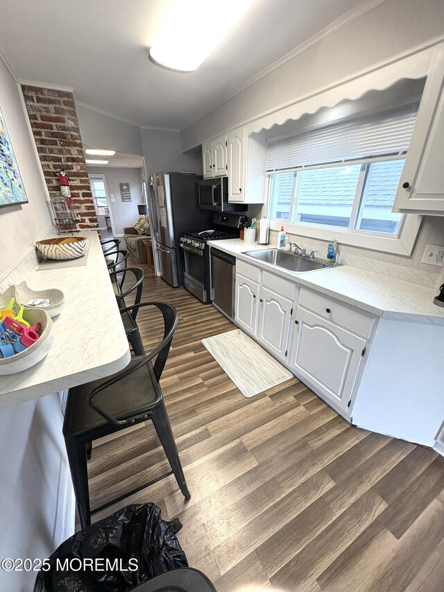25 O St, Seaside Park, NJ 08752 - kitchen with stainless steel appliances, dark wood-type flooring, light countertops, white cabinetry, and crown molding