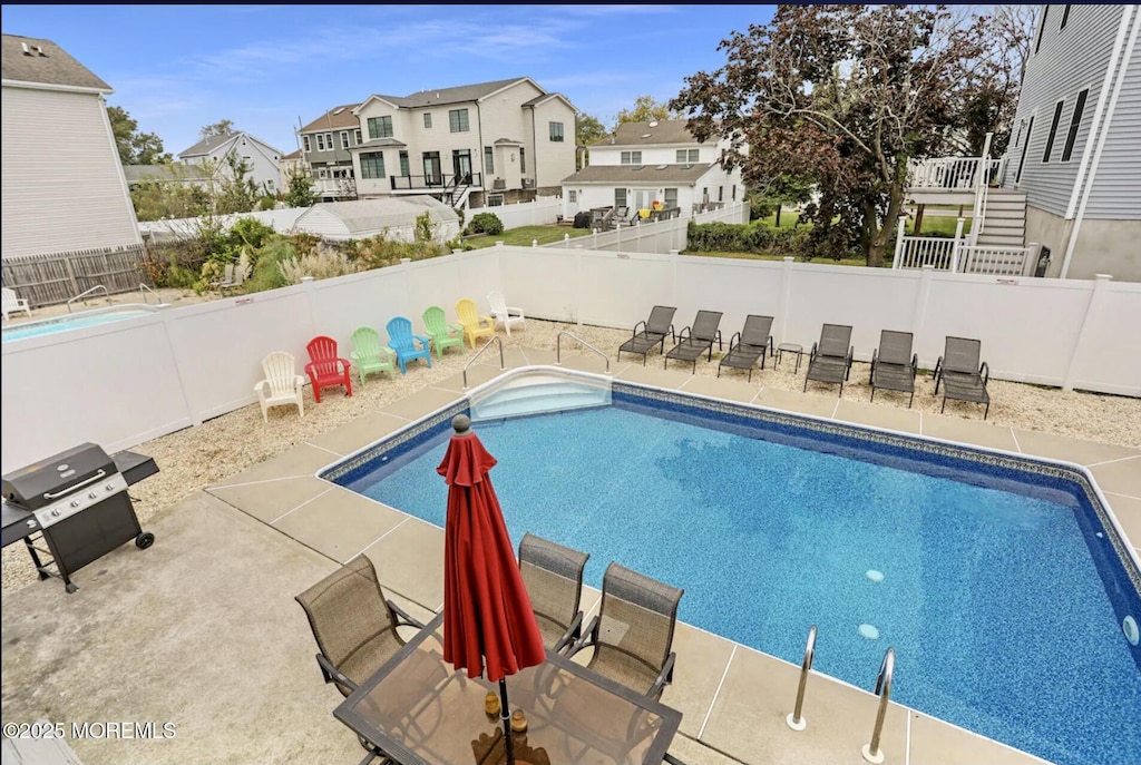 view of swimming pool with grilling area, a residential view, a fenced in pool, a fenced backyard, and a patio