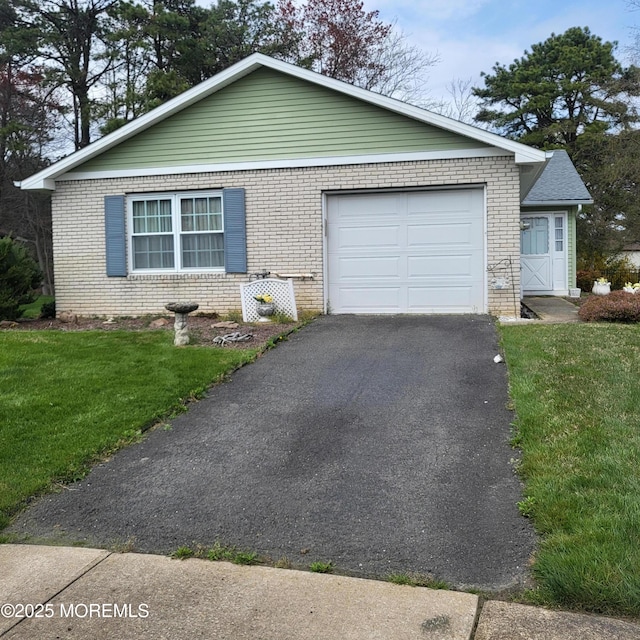 view of front of house with brick siding, an attached garage, a front yard, and aphalt driveway