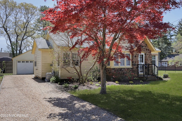 obstructed view of property with a garage, fence, a front yard, stone siding, and driveway