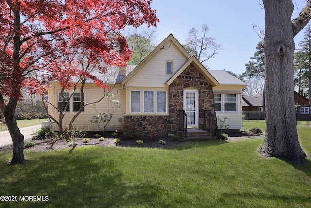 bungalow featuring fence, a front yard, and stone siding