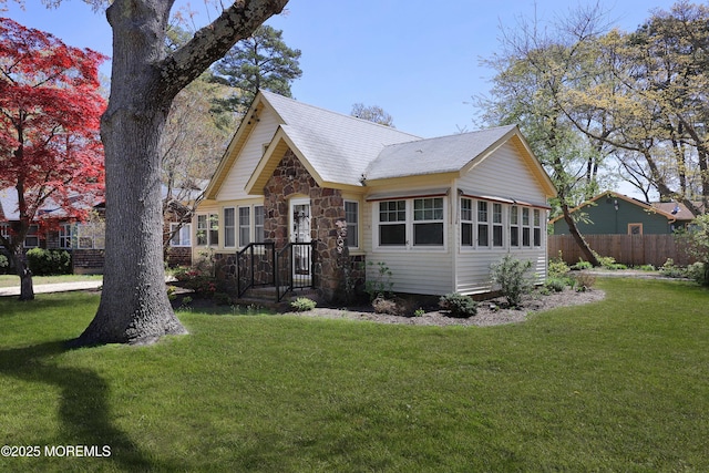 view of front of property featuring fence, a front lawn, and stone siding