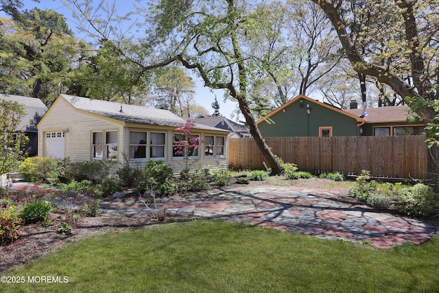rear view of property featuring fence, a lawn, a patio area, and a garage