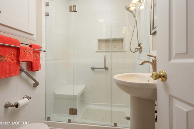 bathroom featuring tile walls, toilet, and a shower stall