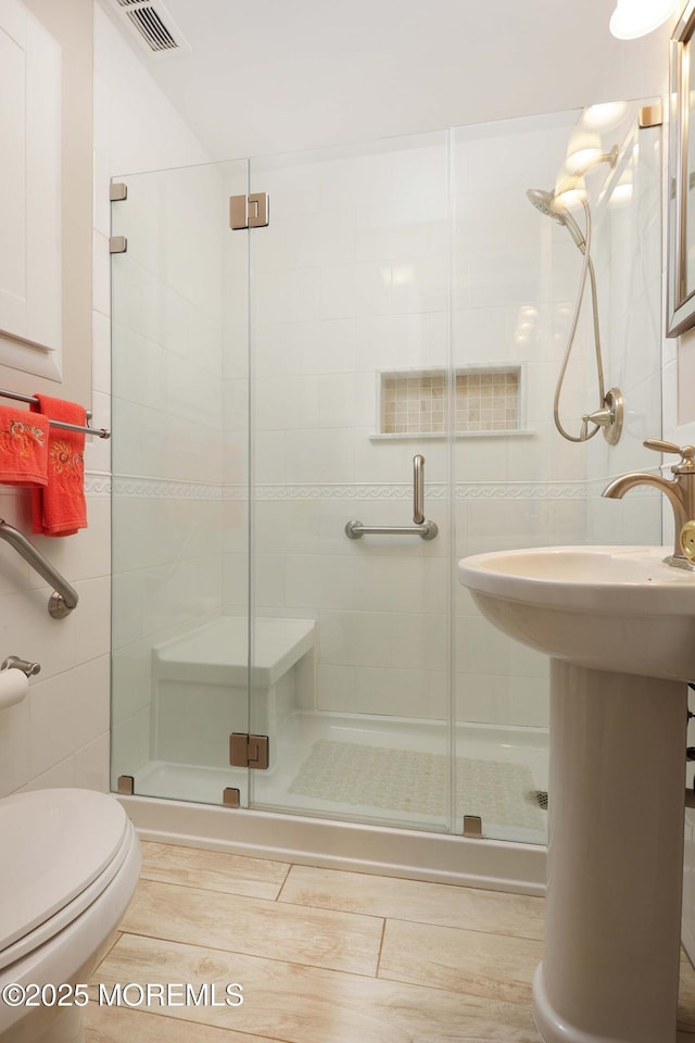 bathroom featuring visible vents, a stall shower, and tile walls