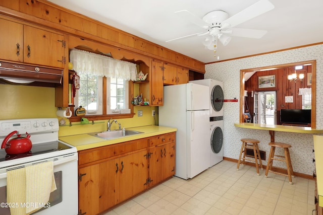 kitchen with stacked washer / drying machine, a sink, ornamental molding, under cabinet range hood, and white appliances