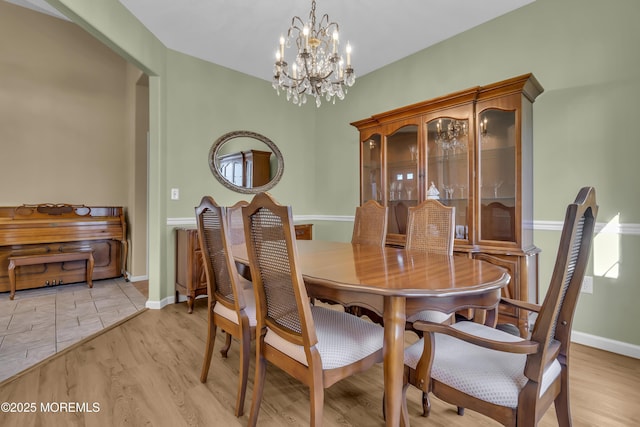 dining space featuring baseboards, light wood-style flooring, and a notable chandelier