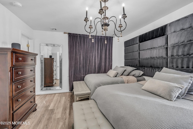bedroom with visible vents, light wood-style flooring, baseboards, and a notable chandelier