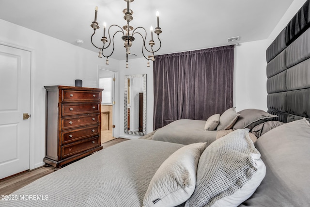 bedroom featuring an inviting chandelier and wood finished floors