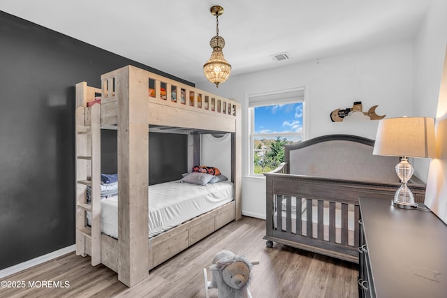 bedroom featuring visible vents, baseboards, and wood finished floors