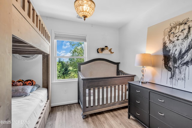 bedroom featuring visible vents, baseboards, an inviting chandelier, and light wood finished floors