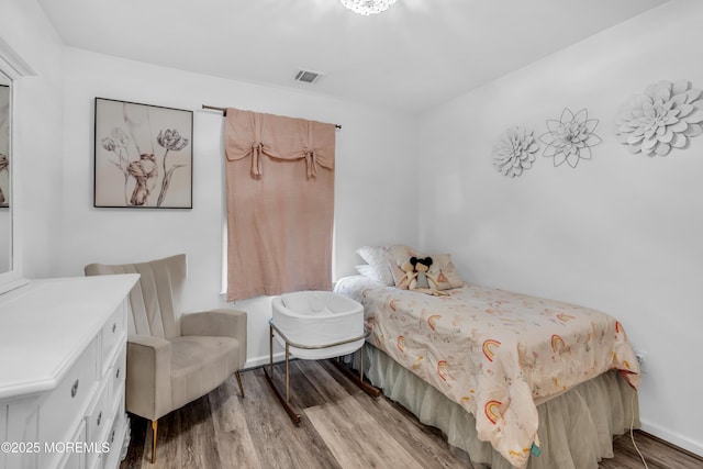 bedroom featuring visible vents, baseboards, and wood finished floors