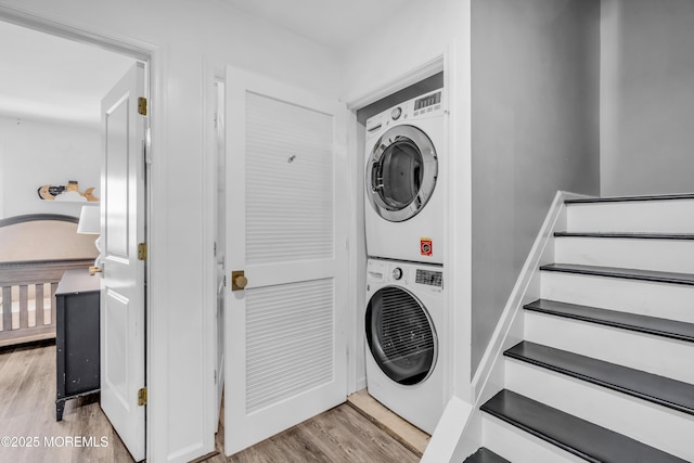 laundry room featuring stacked washer / drying machine, laundry area, and light wood finished floors