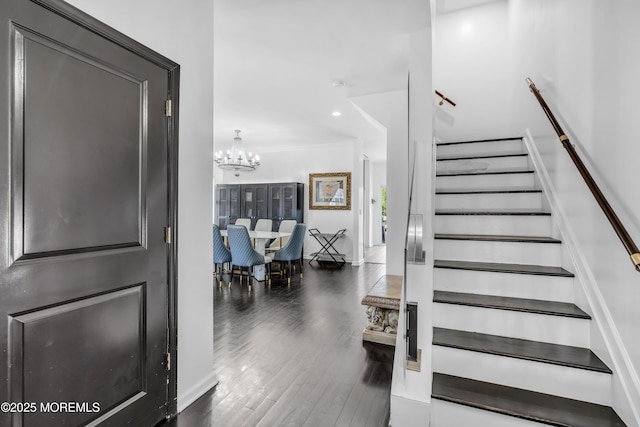 stairs featuring an inviting chandelier and wood finished floors