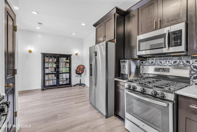 kitchen featuring dark brown cabinets, light wood finished floors, light countertops, stainless steel appliances, and visible vents