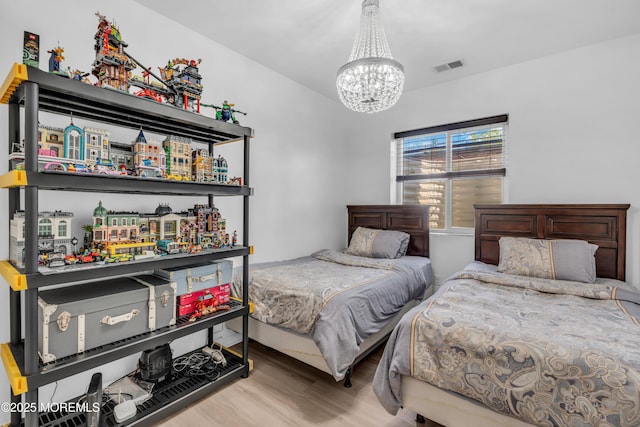 bedroom with a notable chandelier, wood finished floors, and visible vents