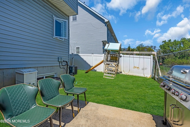 view of yard with a patio, a fenced backyard, a playground, and central AC