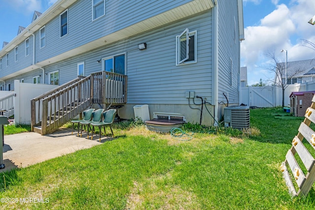 rear view of house with fence, a gate, cooling unit, a patio, and a yard