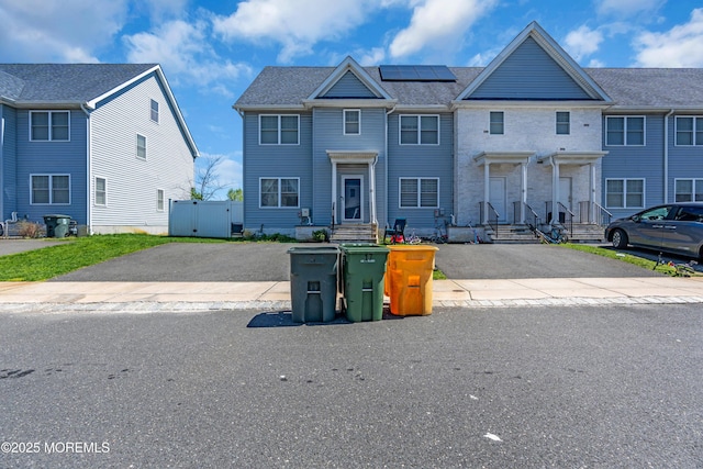 multi unit property with fence, driveway, and solar panels