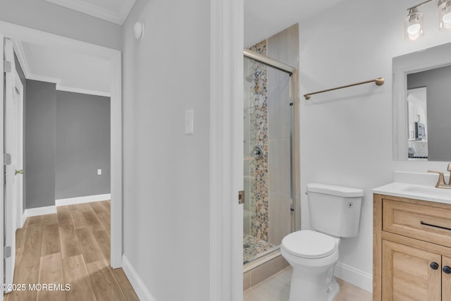 bathroom featuring crown molding, vanity, toilet, a shower stall, and wood finished floors