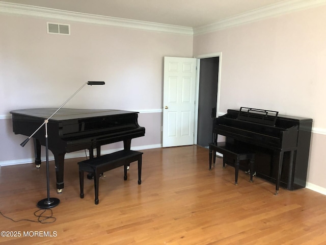 living area with visible vents, ornamental molding, light wood-style flooring, and baseboards