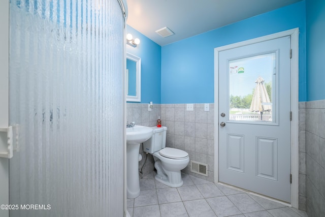 bathroom with visible vents, wainscoting, toilet, tile walls, and tile patterned floors