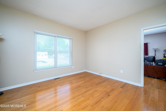 unfurnished room with baseboards, light wood-style flooring, and visible vents